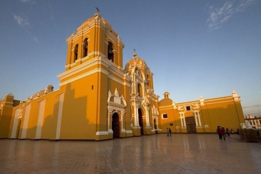 A large yellow building with a bell tower and arched windows. 2