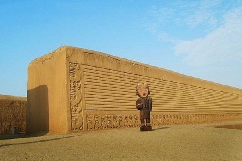 A large, textured wall with horizontal lines and a small figure standing in front. 1