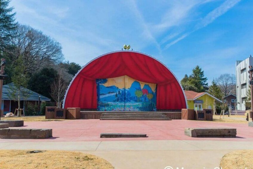 A stage with a red arch and a mural backdrop. 5