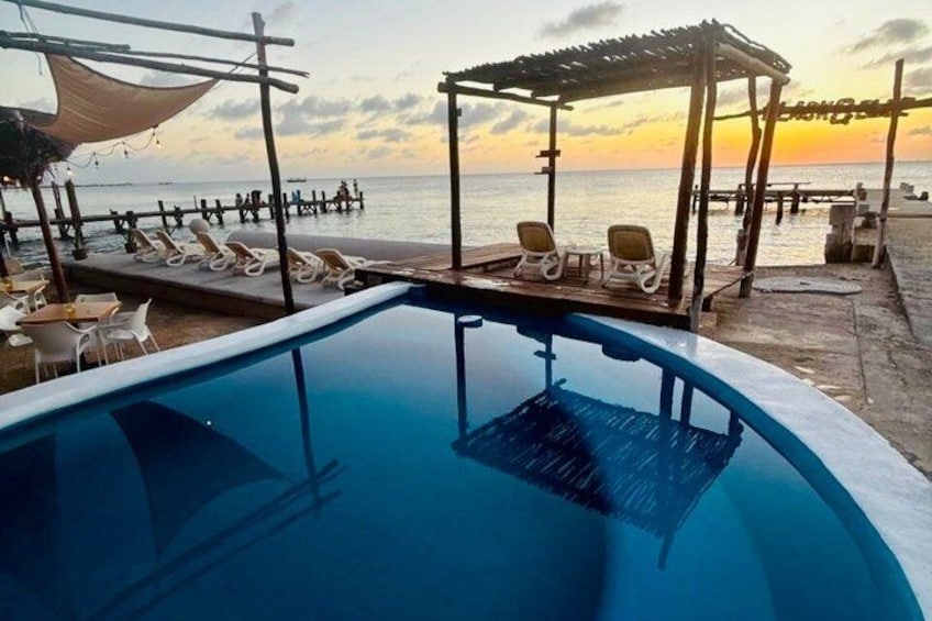 A swimming pool with lounge chairs and a sunset view. 4