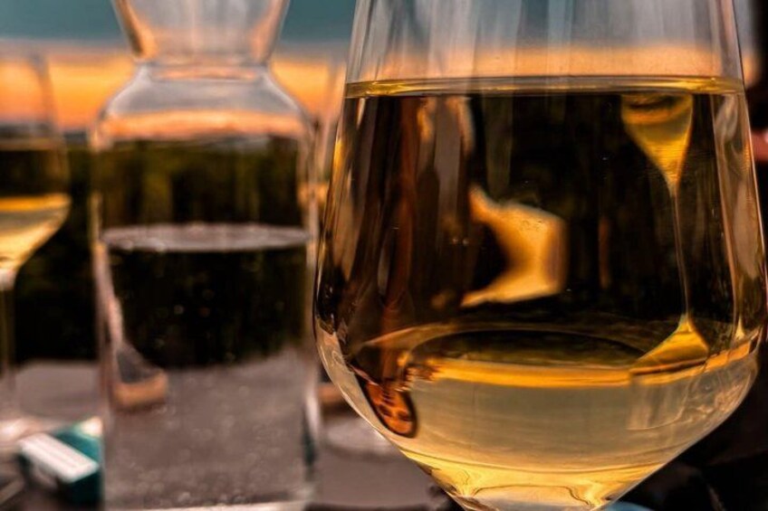 A glass of white wine with a bottle in the background. 2