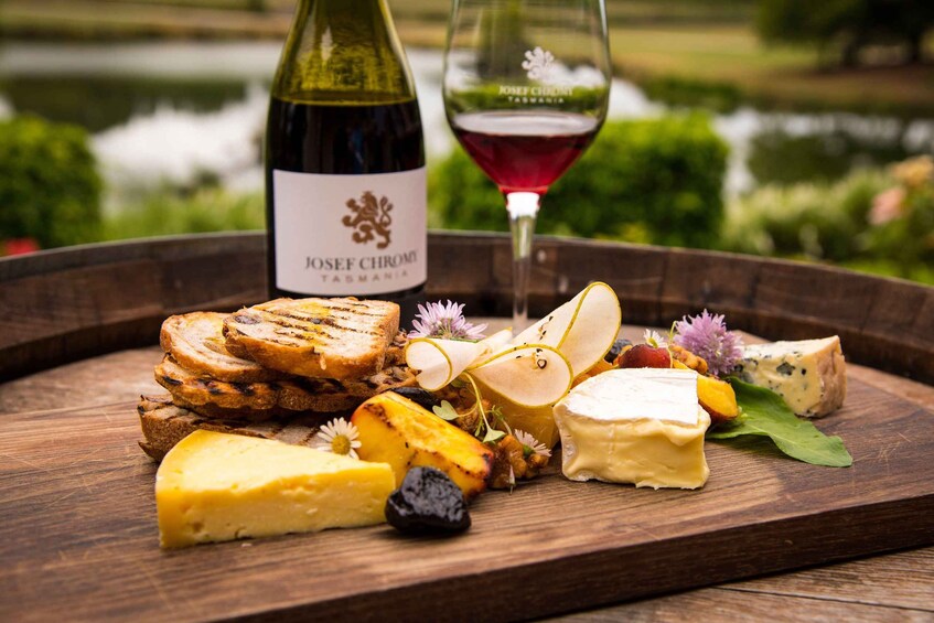 Una tabla de madera con pan a la parrilla, queso y una botella de vino con etiqueta. 5