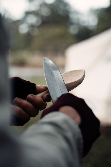 A person sharpening a knife on a wooden sharpening stone. 5