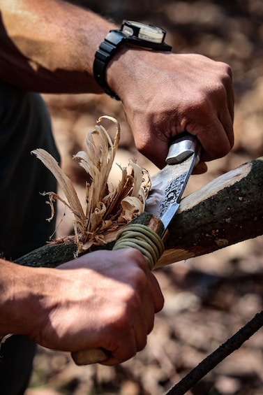 A person carving a wooden branch with a knife. 4