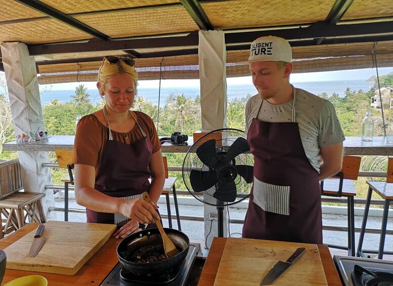 Two people cooking outdoors with a view of the ocean. 4