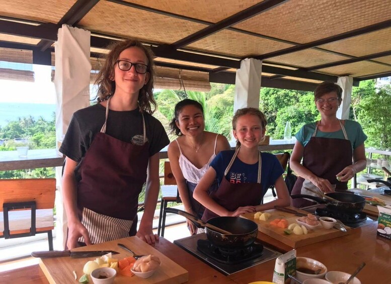Four people cooking outdoors with a view of the ocean. 2