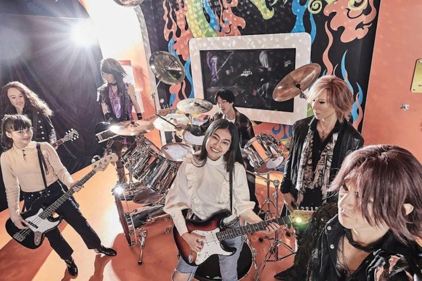 A band performing in a room with musical instruments, a drum set, and a microphone stand. 3