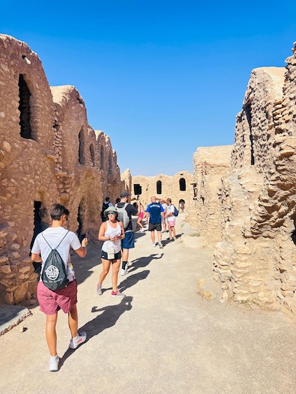 A group of people walking through ancient ruins with stone walls and arched doorways. 2
