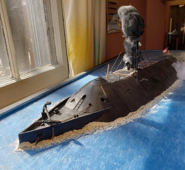A model ship on a blue surface with a window in the background. 3