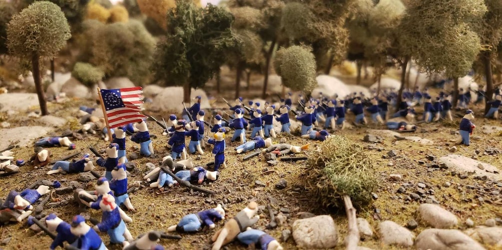 A battlefield with soldiers, fallen comrades, and an American flag. 1