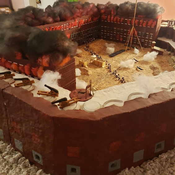 A model of a historical battle scene with miniature figures, wooden structures, and smoke effects. 4