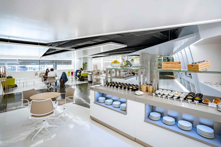 Une cafétéria moderne avec un comptoir en verre où sont exposés les plats et les assiettes. 1