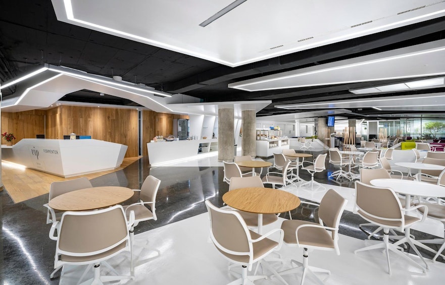 Un espace de bureau moderne avec un comptoir d’accueil, des chaises blanches et des tables. 5