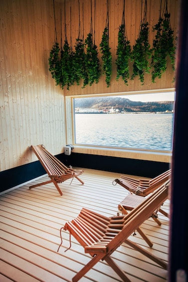 Un terrazzo in legno con due poltrone da relax e piante pensili. 3