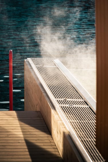 Un pontile di legno che si protende sull'acqua, con un palo rosso e una struttura bianca a listelli. 2