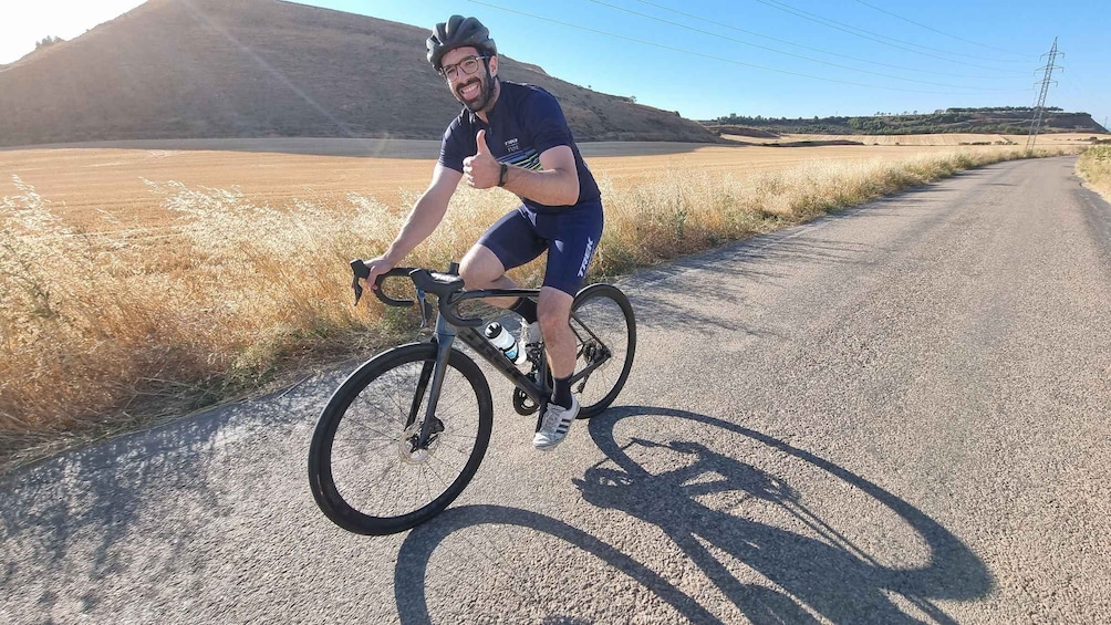 A person riding a bicycle on a gravel road with a hilly landscape in the background. 5