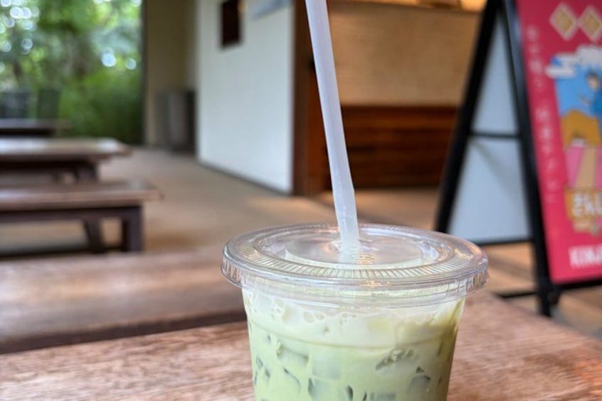 A clear plastic cup with a straw, containing a green beverage, on a wooden table. 3