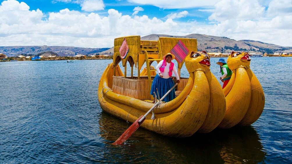 A traditional boat with animal heads, a person in a skirt and hat, and a mountainous landscape in the background. 1
