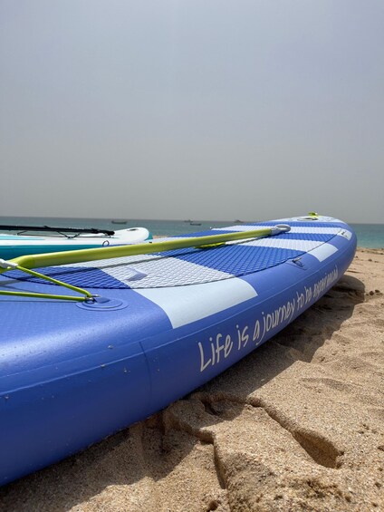 A blue inflatable raft on a sandy beach with the text 'Life is a journey to be experienced' on its side. 5