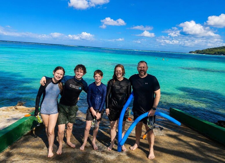 Un gruppo di persone con tavole da surf su una spiaggia con acqua turchese cristallina e un'isola in lontananza. 5