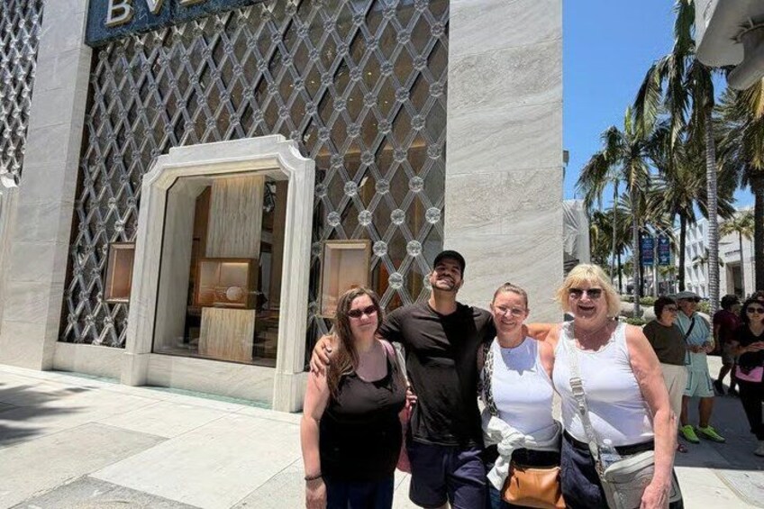 A group of people standing in front of a building with a patterned facade and a large entrance. 3