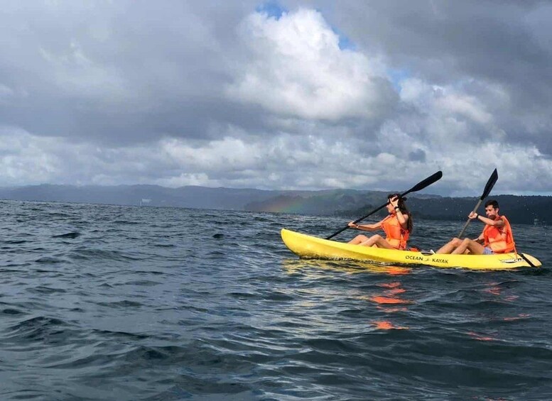 Zwei Personen paddeln mit ihren Kajaks auf dem Wasser, im Hintergrund ein Regenbogen. 2