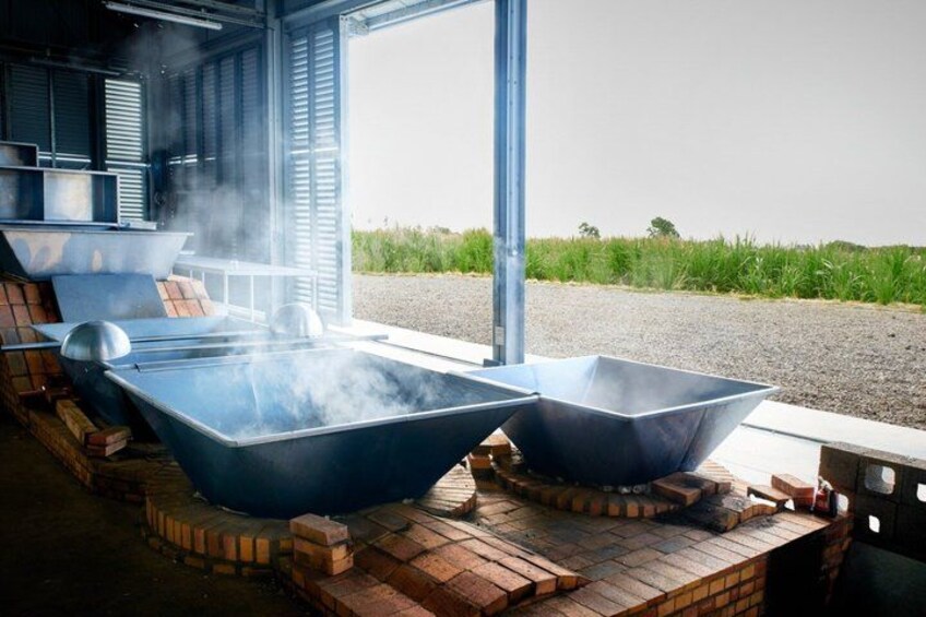 Outdoor hot tubs on brick platforms with steam rising, set against a rural backdrop. 5