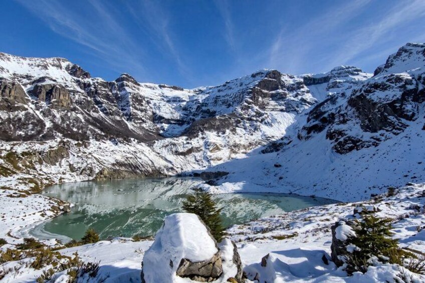 A snow-covered mountain landscape with a turquoise lake and rocky terrain. 4