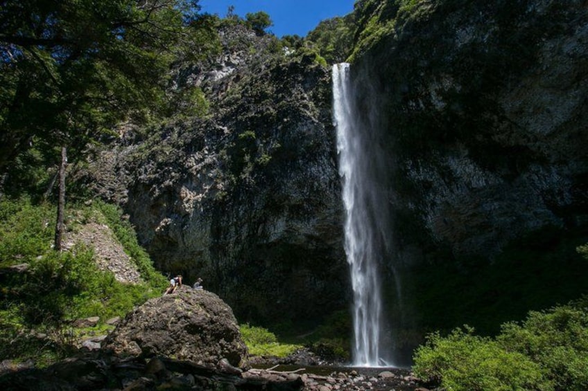 A waterfall cascading down a rocky cliff surrounded by greenery. 2