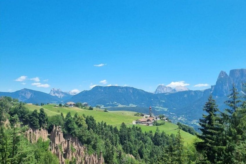 A mountainous landscape with a village, green fields, and a clear blue sky. 1