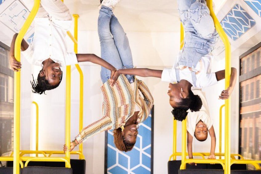 Three people hanging upside down on yellow handrails in an indoor setting. 5
