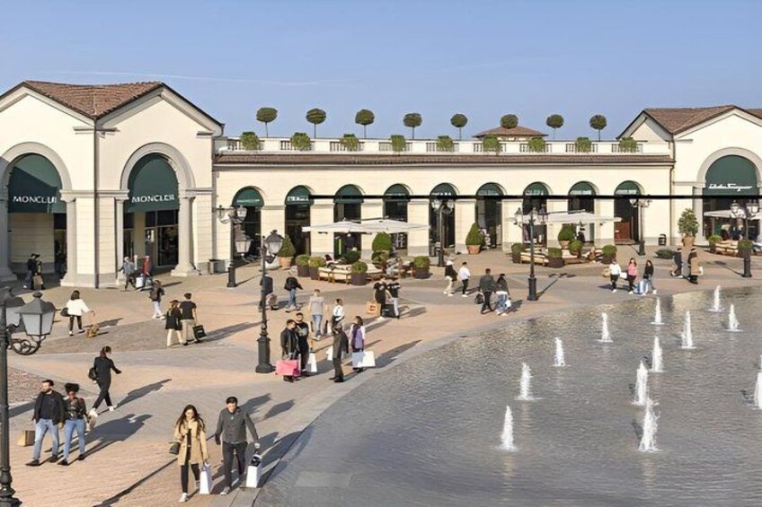 A public square with a fountain, shops, and people walking. 3