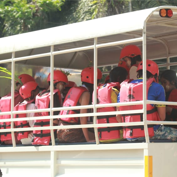 A bus with passengers wearing red helmets and life vests. 3