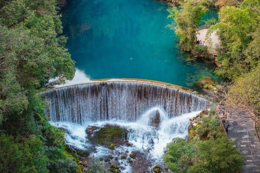A waterfall surrounded by lush greenery and a clear blue pool. 1