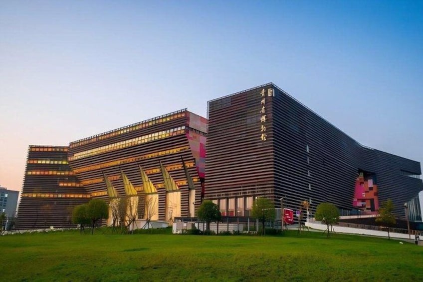 A modern building with a unique architectural design, featuring a large digital display and a prominent red sculpture. 5