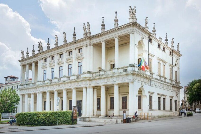 A large, ornate building with columns and statues on the roof. 2