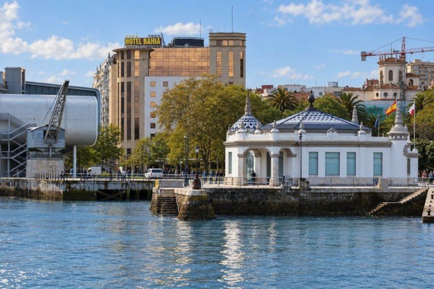 A waterfront with a white building, a large cylindrical structure, and a hotel named 'HOTEL BAHIA' in the background. 2