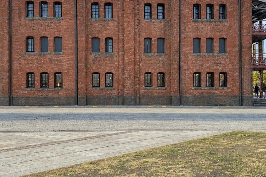 A red brick building with multiple windows and a paved area in front. 3