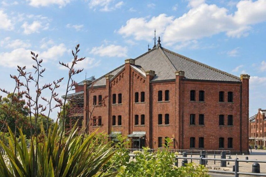 A red brick building with a tiled roof, surrounded by greenery and a clear sky. 5