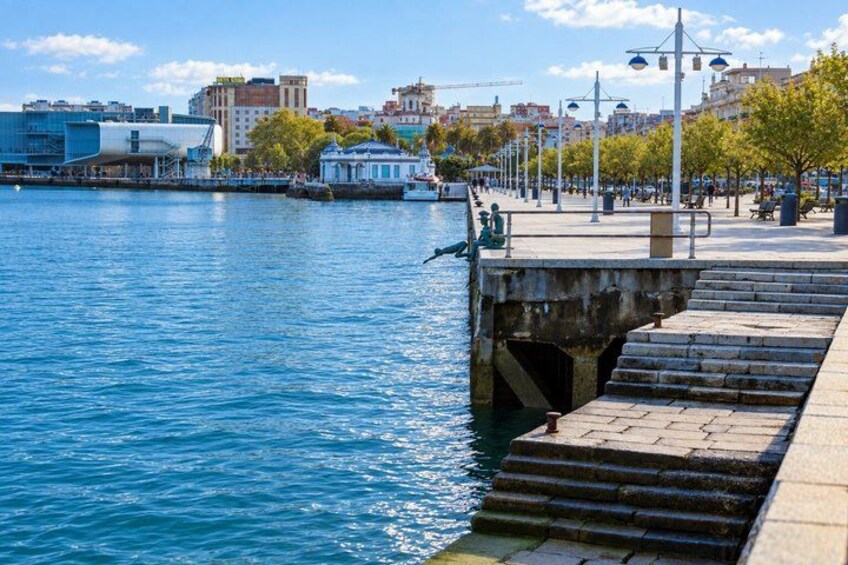 A waterfront promenade with steps leading into the water, a modern building, and a clear sky. 3