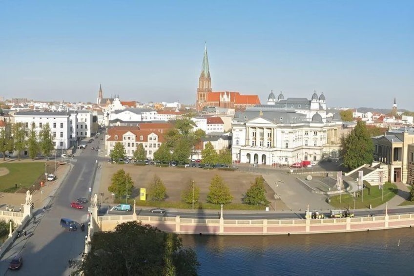 A cityscape with a prominent church steeple, a river, and a bridge. 2