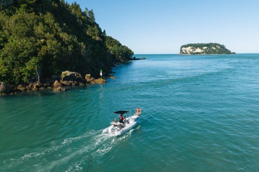 A boat on calm turquoise waters, surrounded by lush green hills and a small island in the distance. 2