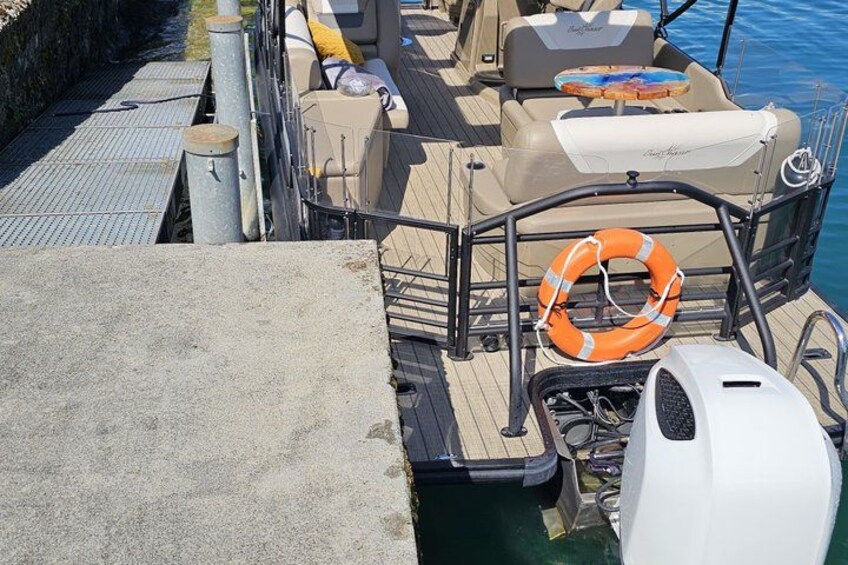 A boat docked at a pier with a lifebuoy, a steering wheel, and a white motor. 2