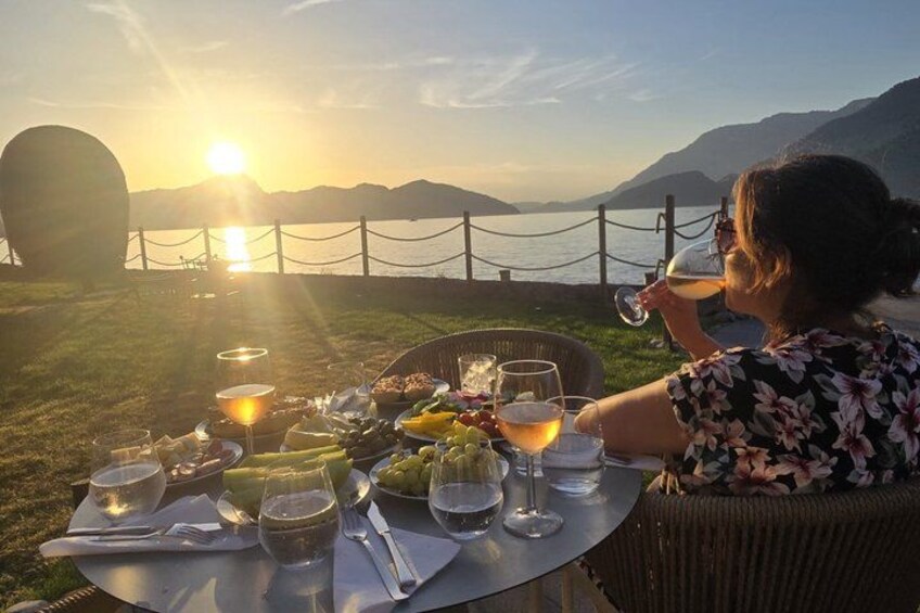 A person dining outdoors with a table set for a meal, a sunset in the background, and mountains in the distance. 4