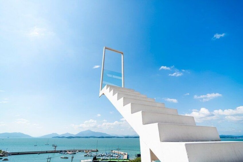 A staircase leading to a balcony overlooking a body of water with boats and mountains in the distance. 2