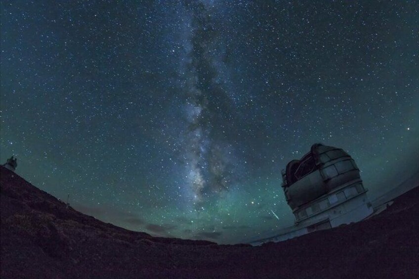 A night sky with stars and the Milky Way, a telescope, and a rocky landscape. 3