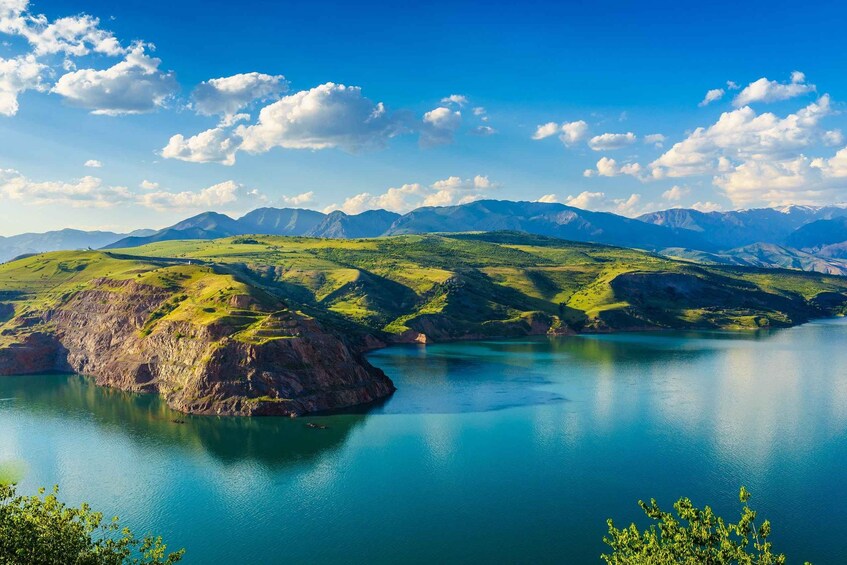 Un paysage montagneux avec un lac, des collines verdoyantes et un ciel dégagé. 3