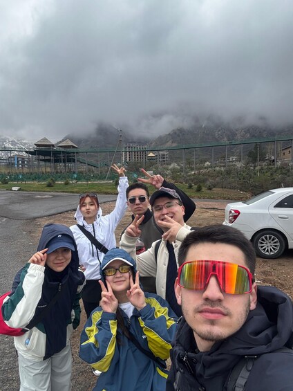 Un groupe de personnes posant pour une photo devant un paysage montagneux, avec un pont en arrière-plan. 5