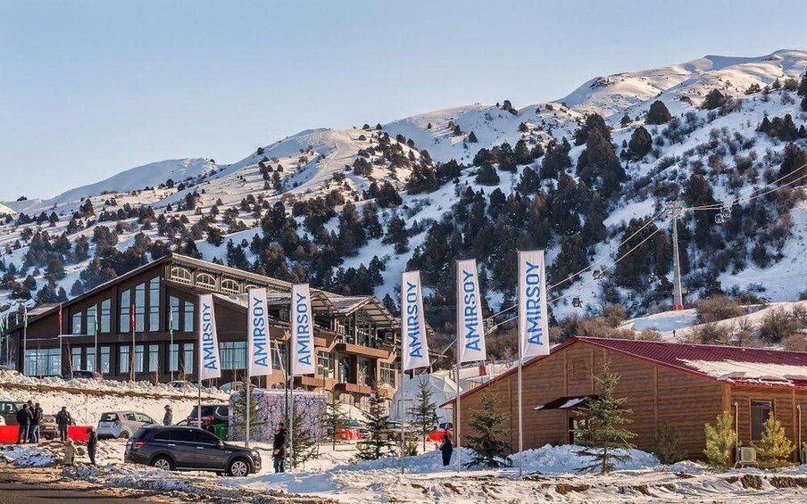 Une station de ski avec des bâtiments et des drapeaux, entourée de montagnes enneigées. 1