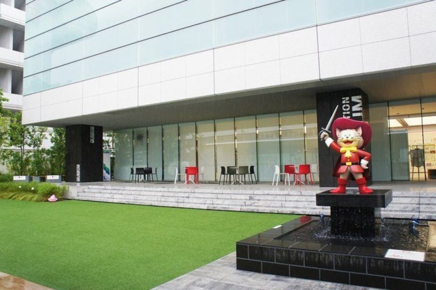 A modern building with a glass facade, a fountain with a statue, and outdoor seating. 2